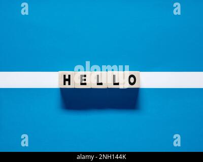 La parola ciao su cubetti di legno su sfondo bianco blu. Ciao saluto o messaggio di saluto per dare il benvenuto a qualcuno o avviare una conversazione. Foto Stock