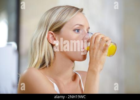 donna che beve una bevanda aromatizzata all'arancia o succo Foto Stock