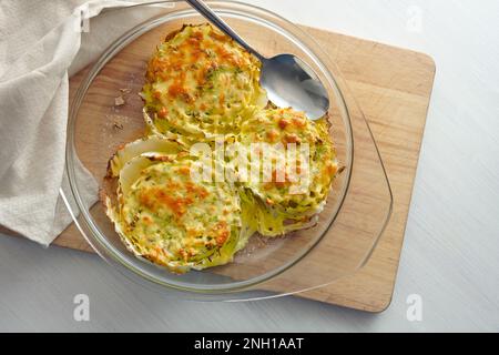 Fettine gratinate di cavolo cinese o nappa in una casseruola di vetro su un tavolo da cucina in legno, piatto vegetariano creativo, vista ad angolo alto dall'alto, poliziotto Foto Stock