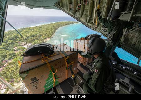 (Da destra a sinistra) Japan Air Self-Defense Force staff Sgt. Ikkei Ono, Tatsuhiro Kurimoto, entrambi gli astronauti tattici del 401st Airlift Squadron C-130H, si sono mossi agli abitanti dell'isola di RUO, lo stato di Chuuuk, Micronesia, 6 dicembre 2022, prima di consegnare tre pacchetti di assistenza umanitaria durante l'operazione Christmas Drop 2022. OCD è la più lunga missione umanitaria e di soccorso in caso di disastri del Dipartimento della Difesa. Ogni anno, l'USAF collabora con i paesi dell'area delle forze aeree del Pacifico per fornire forniture alle isole remote del Pacifico sudorientale Foto Stock