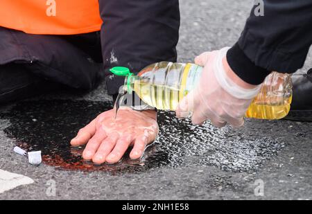 Hannover, Germania. 20th Feb, 2023. Gli agenti di polizia cercano di liberare le mani bloccate degli attivisti del gruppo 'ultima generazione' dalla strada al Deisterkreisel con olio da cucina. Credit: Julian Stratenschulte/dpa/Alamy Live News Foto Stock