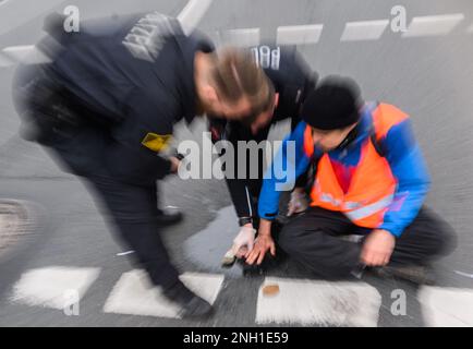 Hannover, Germania. 20th Feb, 2023. Gli agenti di polizia cercano di liberare le mani bloccate degli attivisti del gruppo 'ultima generazione' dalla strada al Deisterkreisel con olio da cucina. Credit: Julian Stratenschulte/dpa/Alamy Live News Foto Stock