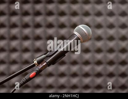 Microfono contemporaneo posizionato nella sala prove contro pareti ruvide nere con messa a fuoco selettiva Foto Stock