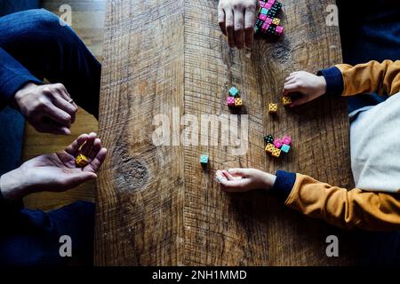 Famiglia caucasica giocando colorato gioco di dadi a tavola di legno caffè Foto Stock