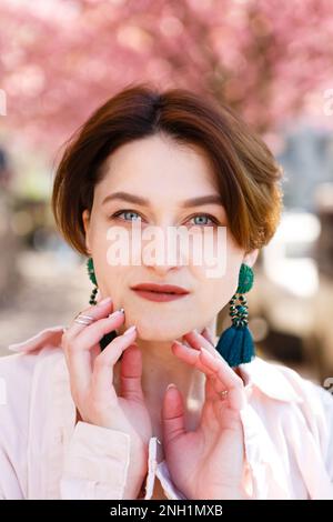 giovane donna dai capelli rossi con occhi blu in una camicia contro in primavera Foto Stock