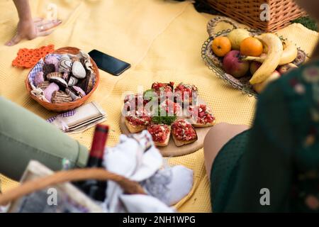 Gruppo di giovani donne in un pic-nic, con bruschetta, dolci e frutta. Foto Stock