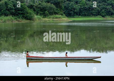 Due ragazze giovani pagaiano una canoa o un cayuco Embera fatto a mano da un singolo tronco di albero scavato, circa 30 piedi di lunghezza. Foto Stock