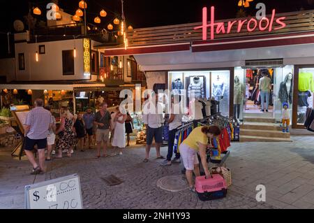 Atmosfera notturna. I turisti passano davanti al negozio di Harrols nel villaggio di Kalkan, Turchia. Luglio 2022 Foto Stock