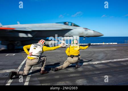 221207-N-MU675-1043 OCEANO PACIFICO (7 dicembre 2022) Capo di comando Joel Rodriguez, a sinistra, da Woodland, Calif., e Lt. CMdR. Andrew Castro, di Knoxville, Tenn., e, segnale a F/A-18E Super Hornet, assegnato a Strike Fighter Squadron (VFA) 14, per lanciare dal ponte di volo della portaerei di classe Nimitz USS Abraham Lincoln (CVN 72). Abraham Lincoln sta conducendo le operazioni di routine nella flotta degli Stati Uniti 3rd. Foto Stock