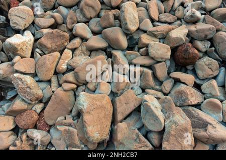 vista ravvicinata dall'alto delle rocce della spiaggia naturalmente arrotondate sulla riva del mare. Foto Stock