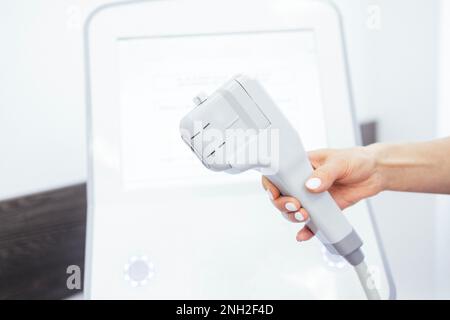 Primo piano di una giovane dottoressa che si prepara al massaggio SMAS ecografico per il sollevamento del viso con attrezzature professionali nel centro di bellezza Foto Stock