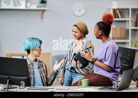 Team eterogeneo di giovani sviluppatori di software che lavorano alla programmazione della realtà virtuale in ufficio Foto Stock