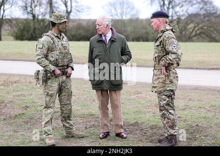 Re Carlo III (centro) incontra il maggiore Tony Harris (a sinistra) prima di un attacco di trincea e di una simulazione di difesa durante una visita a un sito di addestramento per reclute militari ucraine, nel Wiltshire, dove le reclute stanno completando cinque settimane di addestramento di combattimento di base da parte delle forze partner britanniche e internazionali, Prima di tornare a combattere in Ucraina. Data immagine: Lunedì 20 febbraio 2023. Foto Stock