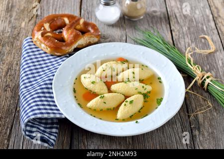 Piatto bavarese, svevo e austriaco - gnocchi di semola in brodo vegetale, serviti con un pretzel croccante Foto Stock