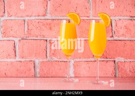 Rinfrescanti cocktail Mimosa all'arancia con champagne su sfondo luminoso. Foto Stock