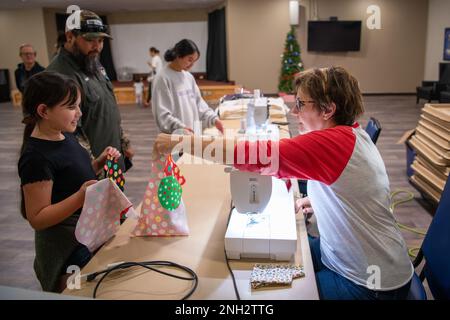 Sandy Carter, volontario fai-da-te Christmas Stocking, consegna a un bambino militare il suo tessuto da calza alla Dyess Air Force base, Texas, 8 dicembre 2022. Dopo aver scelto il loro tessuto, i bambini militari hanno attraversato più stazioni, mentre gli è stato insegnato come le loro calze natalizie sono state messe insieme prima di essere completate. Dopo aver ricevuto le calze, i bambini sono stati anche in grado di scegliere i tessuti per creare calze per un bambino adottivo nella comunità locale. tessuto,vacanze,bambino militare,calza, Foto Stock