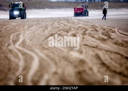 20 febbraio 2023, Meclemburgo-Pomerania occidentale, Rostock: Trattori con grandi rimorchi spargere sabbia sulla spiaggia del Mar Baltico di Warnemünde, lasciando profonde tracce di sabbia. Negli ultimi mesi, le tempeste hanno accumulato alte sottigliature di sabbia davanti al lungomare. Ora questi vengono nuovamente distribuiti sulla spiaggia con escavatori e combinazioni trattore-rimorchio. Foto: Jens Büttner/dpa Foto Stock