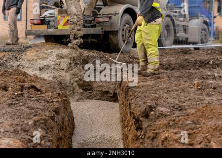 Calcestruzzo semi-secco pronto all'uso consegnato in cantiere e scaricato da il carrello di miscelazione Foto Stock