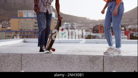 Skateboard, amici e città con un uomo e una donna che pattinano sul tetto all'aperto durante il giorno. Sport, esercizio ed estate con un maschio e una femmina Foto Stock