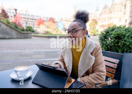 donna felice con cuffie che studiano,imparare a distanza, corso di formazione, lavorare, chattare, guardare formazione online, webinar sull'utilizzo del notebook in un bar Foto Stock