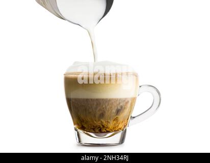 Preparazione del cappuccino in una tazza di vetro con pannarello su sfondo bianco. Foto Stock