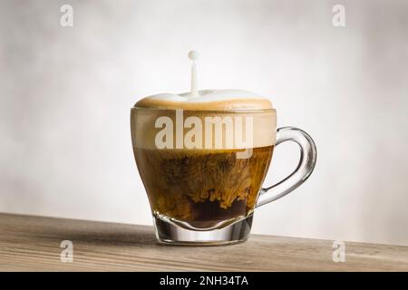 Tazza di cappuccino con il latte spruzzato su un tavolo di legno. Foto Stock