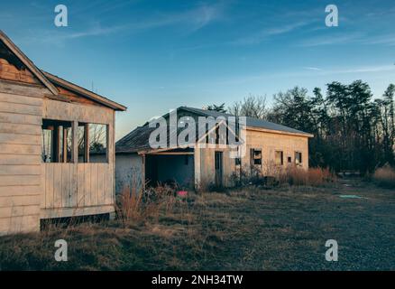 Casa abbandonata e scagliata, illuminata alla luce del sole della sera. Foto Stock