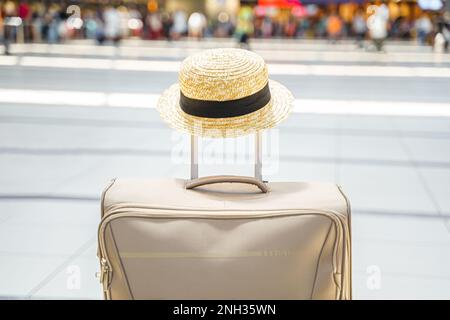 Cappello di paglia sulla valigia grande, borsa nel terminal dell'aeroporto. In attesa dell'imbarco per il volo. Vacanza in famiglia. Check-in bagagli nella sala delle partenze. S Foto Stock