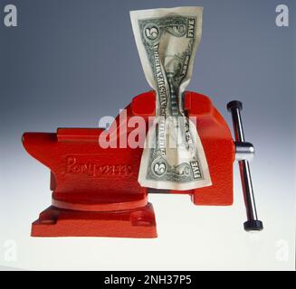 Immagine simbolica del disegno di legge statunitense da cinque dollari che viene spremuto in una morsa Foto Stock