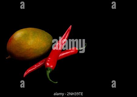 Mango interi e peperoncino su fondo nero. Foto Stock