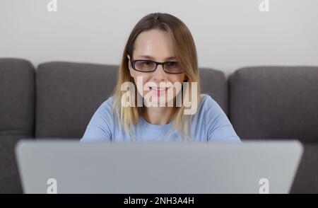 Ritratto di una donna bionda adulta che lavora su un notebook argentato a casa. Primo piano foto di una donna bianca all'inizio del 40s utilizzando un computer notebook moderno per Foto Stock