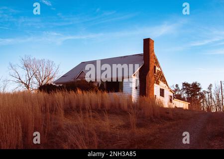 Casa abbandonata e scagliata, illuminata alla luce del sole della sera. Foto Stock