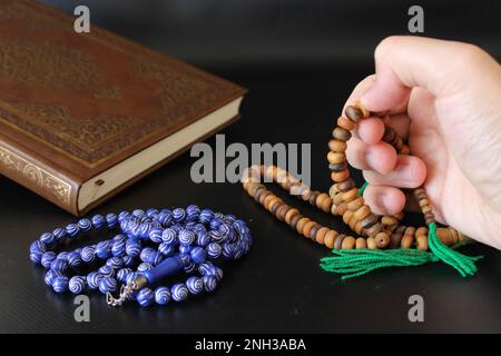 mano di preghiera musulmana con rosario su sfondo quran.consept islamico Foto Stock