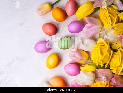 Tulipani colorati e uova di Pasqua su sfondo antico. Festa di Pasqua concetto con spazio copia. Giacitura piatta Foto Stock