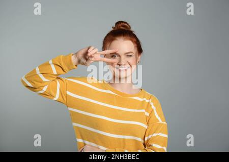 Ritratto di donna dai capelli rossi allegri su sfondo grigio Foto Stock