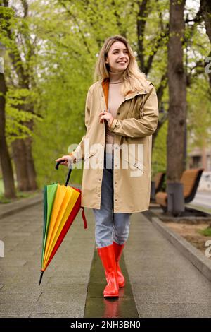 Giovane donna con ombrellone a piedi nel parco il giorno di primavera Foto Stock