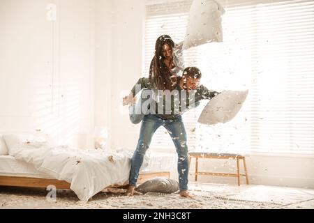 Felice giovane coppia che ha lotta di cuscino divertente in camera da letto Foto Stock