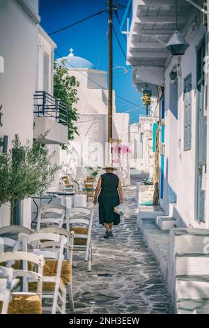 Donna anziana vestita di nero che cammina in un tipico vicolo del villaggio di Chorio, Kimolos Foto Stock