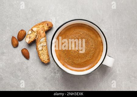 Gustosi cantucci e tazza di caffè aromatico su tavola grigio chiaro, piatto. Biscotti tradizionali alle mandorle italiani Foto Stock