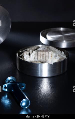 Helsinki / Finlandia - 20 FEBBRAIO 2023 - chiusura di un tino svedese metallico con bustine di snus bianche. Un portatore di snus sciolto blu nel fo Foto Stock