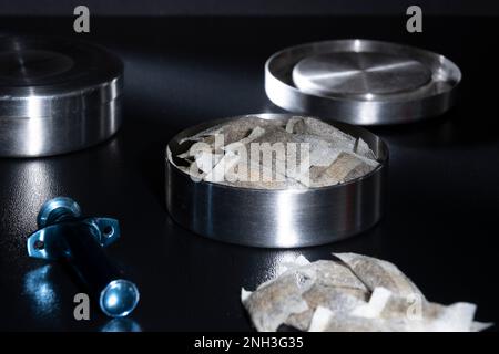 Helsinki / Finlandia - 20 FEBBRAIO 2023 - chiusura di un tino svedese metallico con bustine di snus bianche. Un portatore di snus sciolto blu nel fo Foto Stock