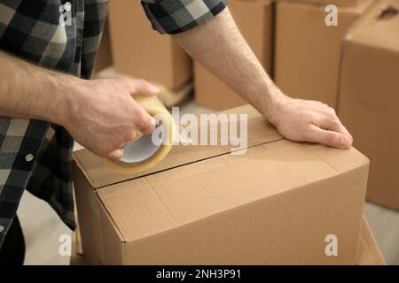 Uomo che nastrano scatola di cartone all'interno, vista primo piano Foto Stock