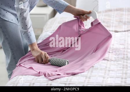 Giovane donna che pulisce i vestiti con il rullo di lanugine a casa, primo piano Foto Stock