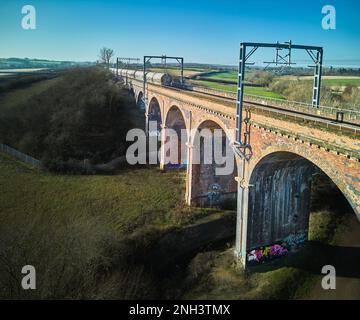 Un treno merci passa attraverso il viadotto ferroviario costruito in mattoni vittoriani a Corby, Inghilterra. Foto Stock