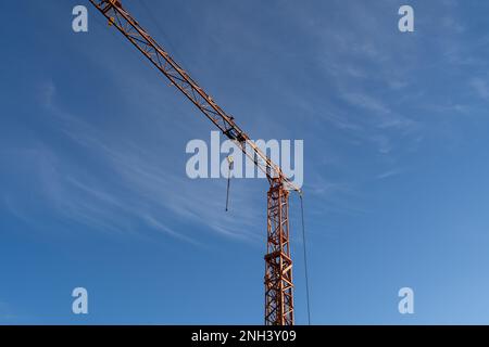 Gru da costruzione alta con un gancio e un bel cielo blu soleggiato sullo sfondo Foto Stock