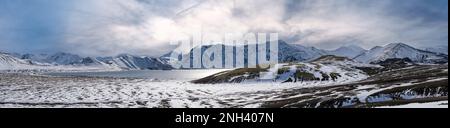 Cambiamenti di stagione negli altopiani islandesi. Montagne Landmannalaugar colorate sotto la copertura di neve in autunno. Lago Frostastadavatn ai piedi del moun Foto Stock