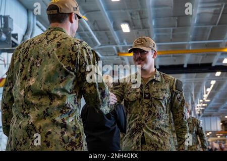 221210-N-DF558-1286 OCEANO PACIFICO (10 dicembre 2022) il capitano Patrick Baker, partito, ufficiale esecutivo della portaerei di classe Nimitz USS Abraham Lincoln (CVN 72), si congratula con lo specialista della comunicazione di massa 3rd Classe Jett Morgan, a destra, da Lafayette, in la, durante una cerimonia di frocking nella baia di hangar a bordo della portaerei di classe Nimitz USS Abraham Lincoln (CVN 72). Abraham Lincoln sta conducendo le operazioni di routine nella flotta degli Stati Uniti 3rd. Foto Stock