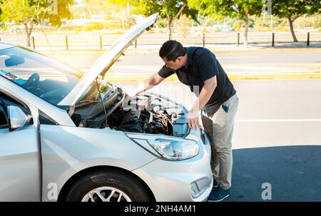 Controllo dell'olio del veicolo da parte del conducente. Persona che controlla il livello dell'olio della sua auto in strada. Il conducente ispeziona il livello dell'olio della vettura Foto Stock