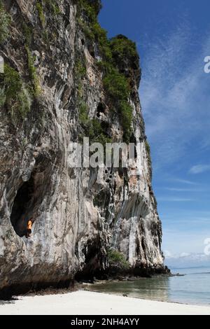 Uomo tailandese in una grotta nella roccia carsica e spiaggia di sabbia bianca sul mare cristallino, Koh Lao Liang, Mare delle Andamane, Thailandia meridionale, Thailandia Foto Stock