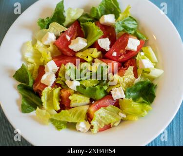 Insalata fresca con lattuga romana, pomodori tagliati e feta in un recipiente bianco. Primo piano, dall'alto. Foto Stock